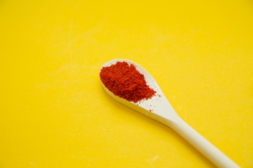 Wooden spoon with dry spices and fresh herbs on a yellow background with copy space, top view, close up