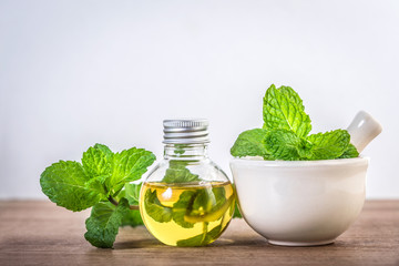 Aroma essential oil from a peppermint in the bottle on the table with fresh green mint leaf
