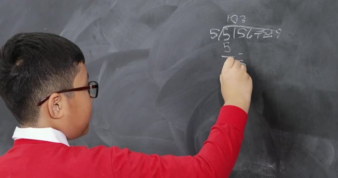 Smart Asian student working on a Math question on a blackboard