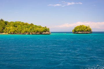 Togian Islands travel destination, Togean Islands scenic beach and coastline with lush green jungle in turquoise sea, Sulawesi, Indonesia.
