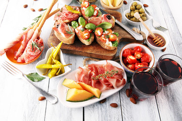 Italian antipasti wine snacks set. Cheese variety, Mediterranean olives, pickles, Prosciutto di Parma, tomatoes, artichokes and wine in glasses