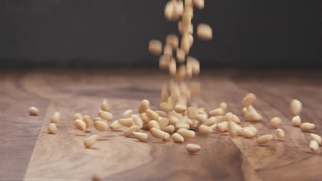 Slow motion pine nuts falling on wood table