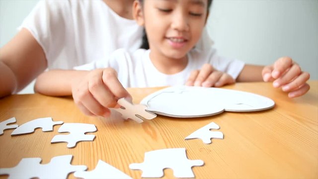4K Asian little girl playing jigsaw puzzle with mother