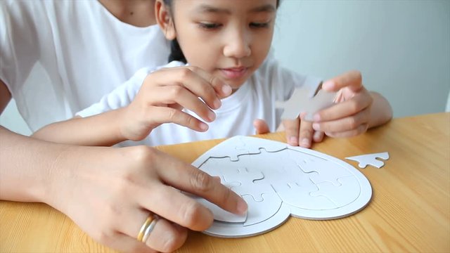 4K Asian little girl playing jigsaw puzzle with mother