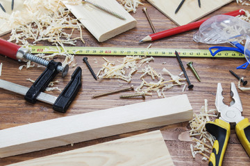 Electric jigsaw with many wooden bricks full of sawdust. On old scratched wooden table, work tools concept