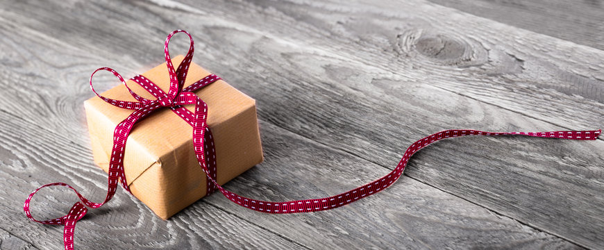 Paket mit roter Schleife auf rustikalem Holz  --  Hintergrund, Banner