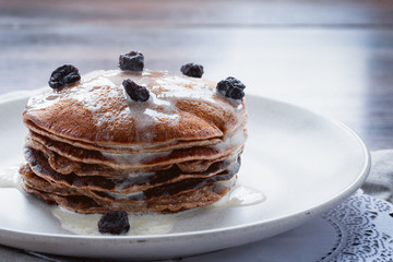Homemade pancakes or russian blini with coconut cream, maple syrup and dried blueberries. Vegan...