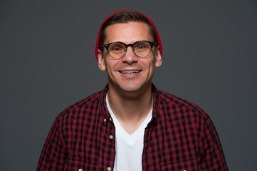 Portrait of young stylish hipster guy wearing glasses looking at the camera on gray background