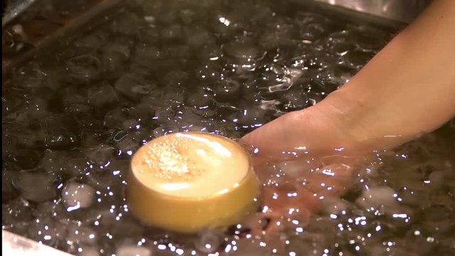 Chilling glass of beer in cool water. Wine glass of beer cooling in water with ice cubes.