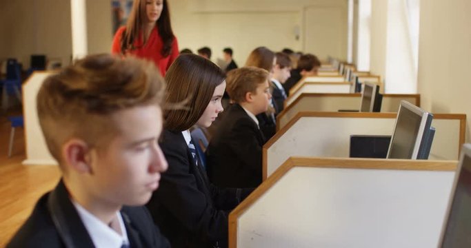 4k, Happy and cheerful young female teacher helping a school student in a computer lab.