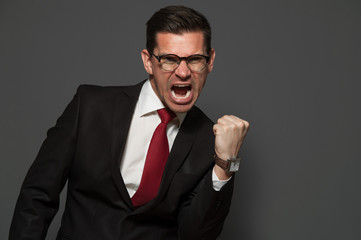 Portrait of emotional businessman with glasses and formal suit shouting with joy, screams yes for joy.