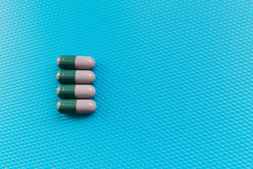 medicines in the form of capsules, gray green capsules on blue background