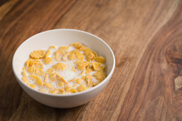 corn flakes poured with milk in white bowl on table