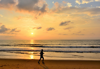Fototapeta na wymiar Silhouette of men are jogging on the beach sunset background