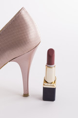 High-heeled women's shoes and lipstick white background