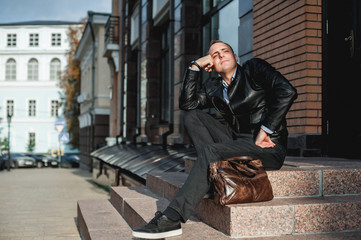 a young man in a leather jacket and with a bag
