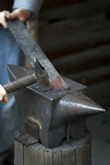 A blacksmith works the incandescent iron with anvil and hammer