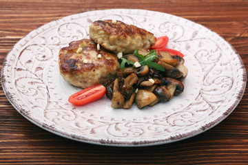 Roasted chicken cutlet with garnish with mushrooms on old wooden