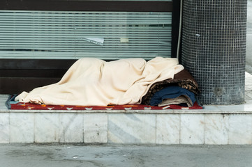 Homeless man or woman, Poor homeless or refugee person covered with a blanket sleep in the shadow on the street