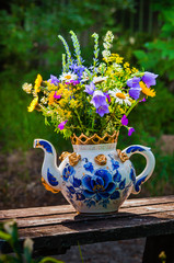 A beautiful bouquet of wildflowers in a large teapot used as a vase. 2