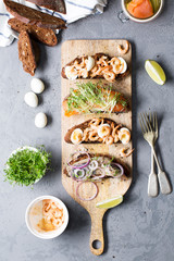 Open sandwiches with herring and onions, salmon, shrimps with rye bread, vertical, selective focus