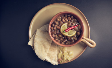 A high angle view/color image of Egyptian, Arabian, Middle Eastern Traditional food (Fava Beans with Lemon and Chili Red Paprika) A.K.A (Foul) - Also served in Lebanon, Iraq, Emirates and most of Arab