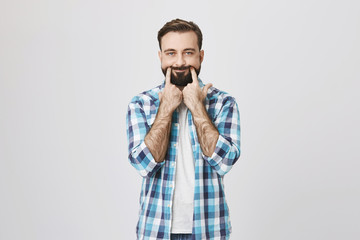 Gloomy and tired european man making fake smile gesture via stretching mouth with hands. Employee can not bear to express happiness all day long in front of customers