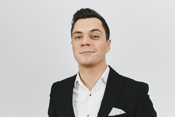 Close-up portrait of stylish trendy young brunette man a in white shirt and black suit on white background