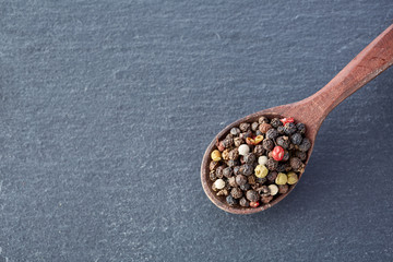 Fototapeta na wymiar Chinese pepper, Sichuan pepper in wooden spoon on black slate stone plate