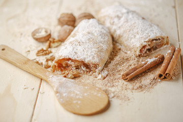 Fototapeta na wymiar Apple strudel with nuts, raisins, cinnamon and powdered sugar.