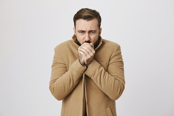 Close up portrait of mature male who feels very cold outside over white background. Man hopes that he will not get cold. Who knew that this day is bad for a date outside.