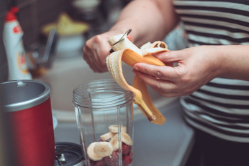 Close up of woman making fruit smoothie in the kitchen.