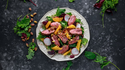 Duck breast fillets steak salad with orange halves, radishes and crushed pistachios