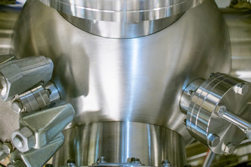 Detail of vacuum equipment featuring steel flanges and pipelines bolted to the vessel in laboratory or industrial environment. Industry or technology background.