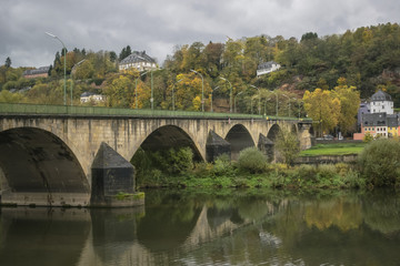 Fototapeta premium Detail of Moselle river valley with bridge and village houses near Trier in rainy day in November, Germany. Dark autumn landscape.