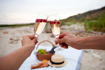 Two glasses of champagne. Picnic on the beach at sunset in the white plaid, food and drink conception