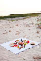 Picnic on the beach at sunset in the white plaid, food and drink conception