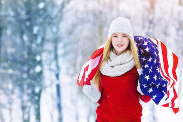 Winter portrait of young teen girl with USA flag. Beauty Joyful Model Girl laughing and having fun in winter park. Beautiful young woman outdoors. Enjoying nature, wintertime
