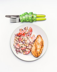 Healthy dieting meal . Chickpeas salad and grilled chicken breast with cutlery and measuring tape on white background, top view