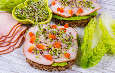 Sandwiches with lettuce, ham and broccoli sprouts.