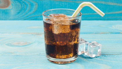 Sweet, fizzy drink with ice on a blue background.