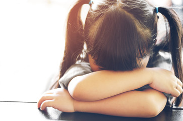 Asian children cute or kid girl sleeping and cry with sad or sick on the black table at nursery or kindergarten and preschool with sunlight and space on vintage