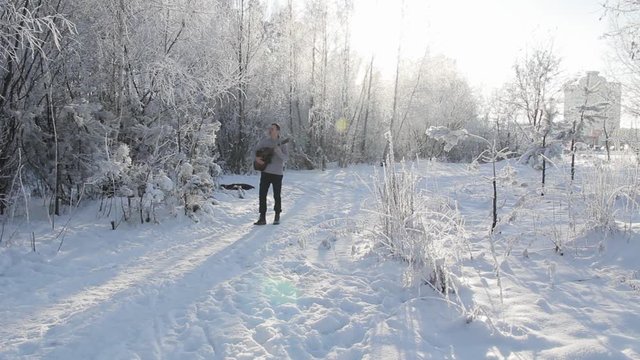 young guy in the snow-covered forest playing the guitar
