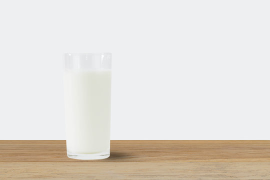 Fresh milk in glass on wooden table on white background
