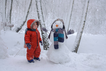 European boy and the snowman in a snowy forest