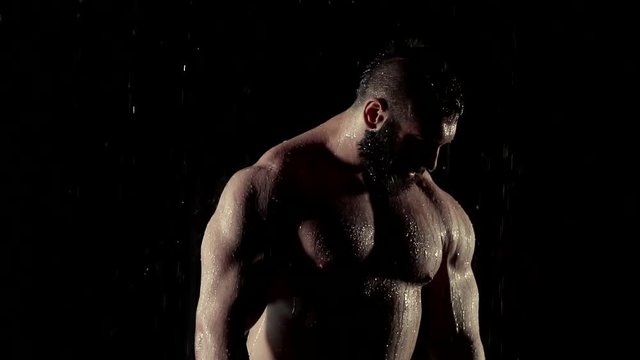 a portrait of a brutal person with an inflated torso and the muscles of the press, on whom the rain falls