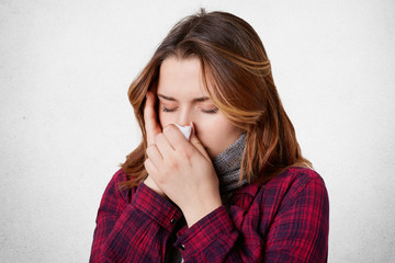 Indoor shot of female with fever and headache, uses tissue and sneezes all time, has running nose...