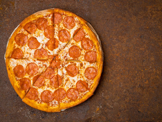 round Italian pizza pepperoni on a rusty metal desk top view, empty space for text.