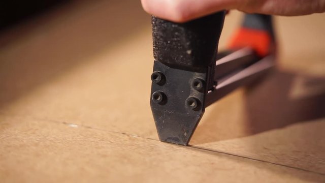 Close up shot of handyman using industrial staple gun in a carpentry workshop. Stapling plywood with a wood construction.
