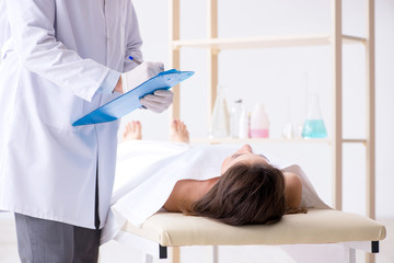 Police coroner examining dead body corpse in morgue